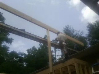 Carpenter setting a ridge beam over a new addition frame — Ice Dam Removal by Roofing Brothers in Stedman