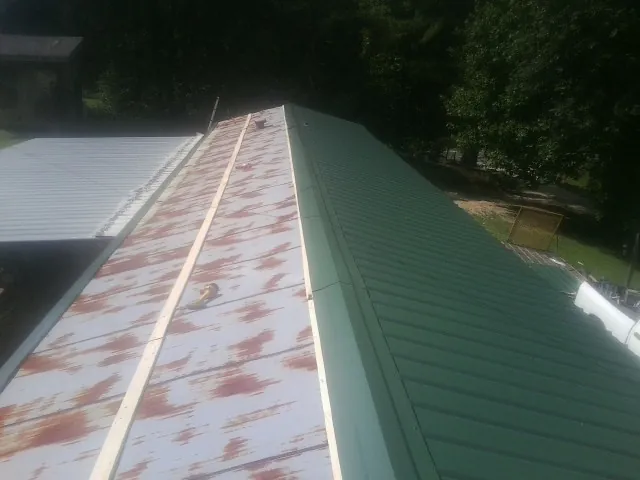 Old rusted panels beside newly installed green metal roofing — Wind Damage Roof Repair by Roofing Brothers in Stedman