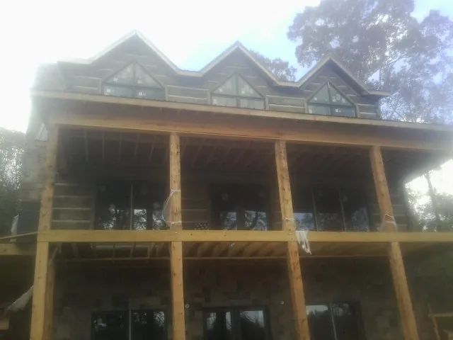 Dormers and porch framing on a large log home under construction — Roof Coating work by our crew in Stedman