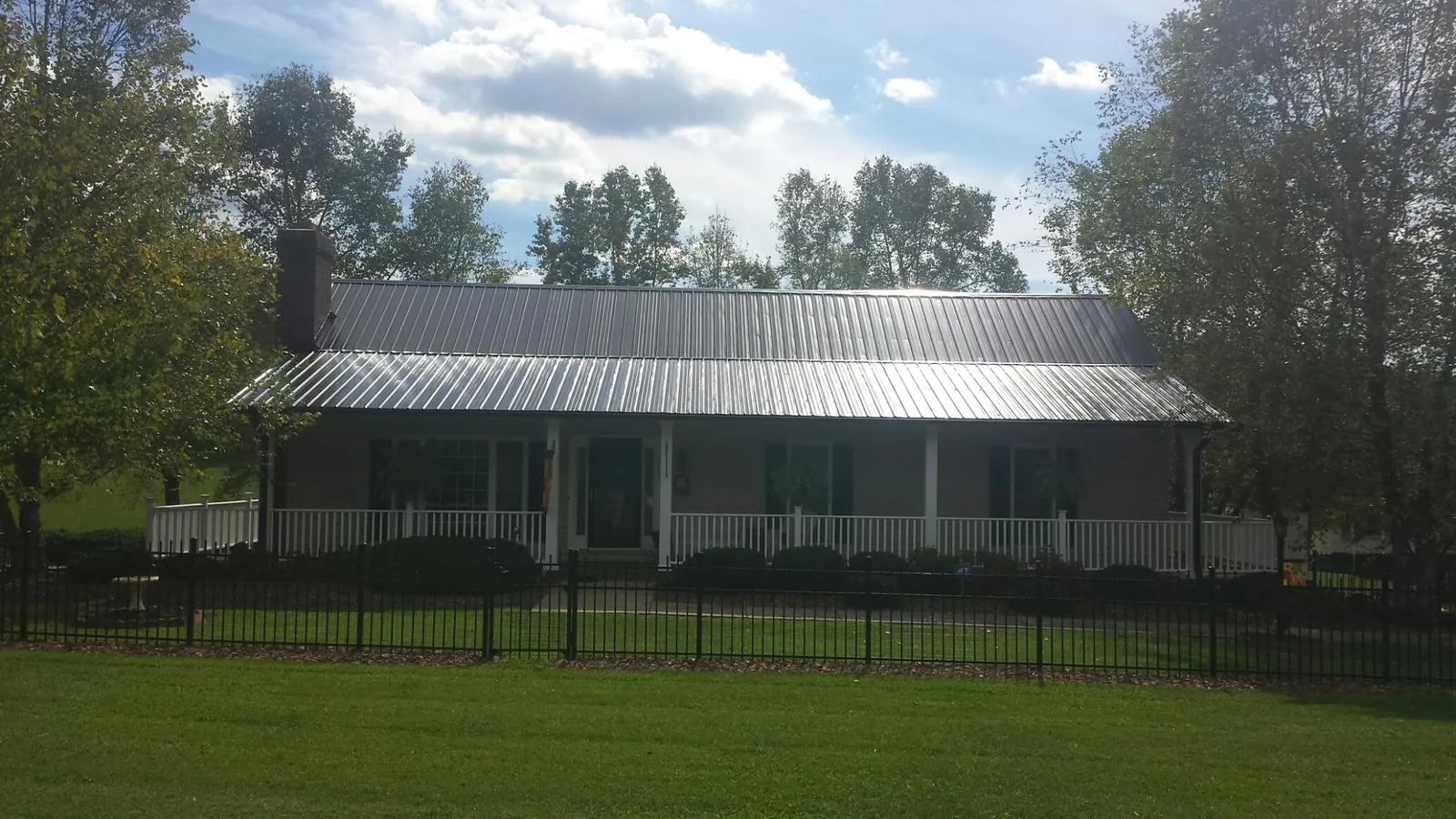 Gray metal roof on a brick ranch with a full width front porch — Gutter Guard Installation work by our crew in Stedman