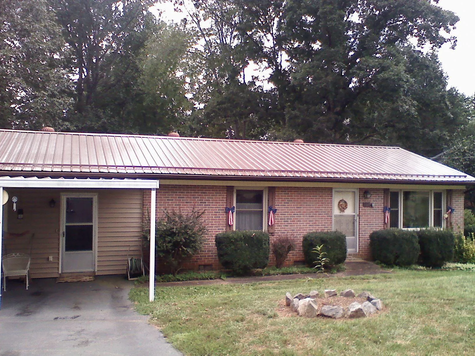 Bronze metal roof and carport on a brick ranch home — Roof Repair work by our crew in Stedman