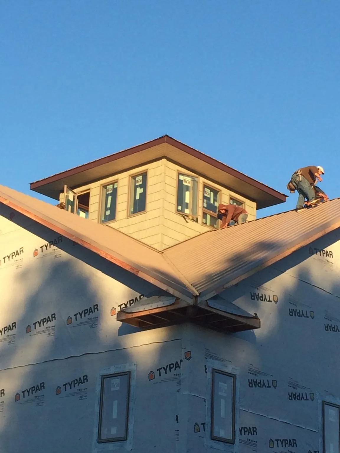 Roofers working around a rooftop cupola on a new metal roof at sunset — Roof Waterproofing in Stedman by Roofing Brothers